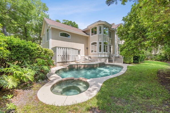 A two-story house with a swimming pool and a covered patio area.