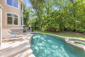 A swimming pool with clear water, surrounded by a well-maintained lawn and trees.