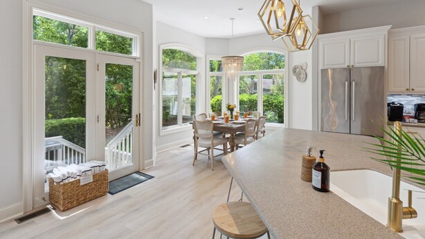 A spacious kitchen with a large island, white cabinetry, and a view of a lush garden.