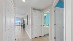 A hallway with white doors, a view to the outside, and a bathroom with a blue accent wall. - Amazing 2BR Beachfront Condo in the Heart of Destin (Destin)