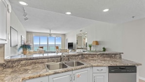 A modern kitchen with granite countertops, a dishwasher, and a view of the ocean. - Amazing 2BR Beachfront Condo in the Heart of Destin (Destin)