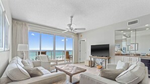 A spacious living room with a large TV, comfortable seating, and a balcony with a view of the ocean. - Amazing 2BR Beachfront Condo in the Heart of Destin (Destin)
