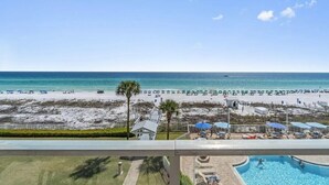 A beach view from a balcony with a pool, umbrellas, and lounge chairs. - Amazing 2BR Beachfront Condo in the Heart of Destin (Destin)
