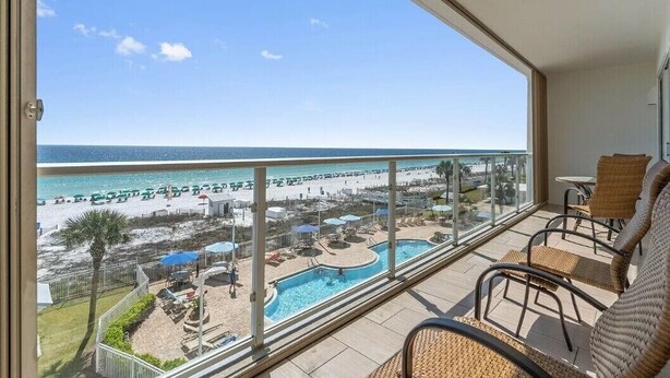A balcony with a view of a beach and a pool. - Amazing 2BR Beachfront Condo in the Heart of Destin (Destin)