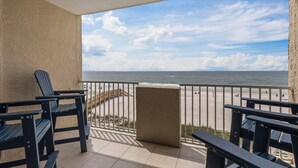 A balcony with two Adirondack chairs, a wooden deck, and a view of the beach and ocean. - BEACHFRONT CONDO, FAMILY FRIENDLY, LOW FLOOR, OUTDOOR POOL (Gulf Shores)