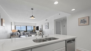 A modern kitchen with a large island, built-in dishwasher, and a view to the living area. - BEACHFRONT CONDO, FAMILY FRIENDLY, LOW FLOOR, OUTDOOR POOL (Gulf Shores)