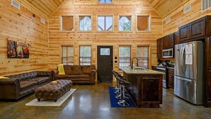 A log cabin interior with a living room, kitchen, and a loft bedroom area. - Crystal Moon - Hot Tub, Firepit, Cornhole, Hammock (Broken Bow)