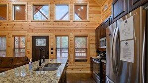A kitchen with granite countertops, stainless steel appliances, and wooden paneling. - Crystal Moon - Hot Tub, Firepit, Cornhole, Hammock (Broken Bow)