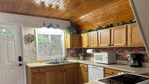 A kitchen with wooden cabinets, a white microwave, a coffee maker, and a sink.