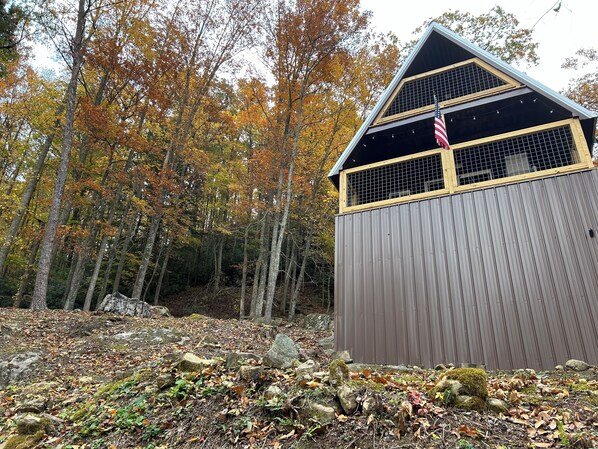 A wooden cabin with a sloped roof and a window with a metal grid.
