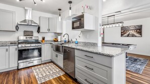 A modern kitchen with stainless steel appliances, a built-in microwave, and pendant lighting.