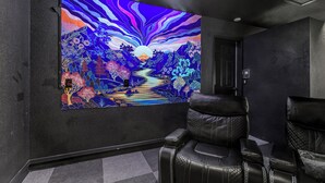 A room with a large wall mural depicting a landscape scene, black leather seating, and a door in the background.