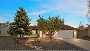 A residential house with a driveway, a tree, and a well-maintained lawn.