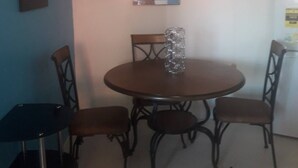 A dining area with a round table and four chairs, a small refrigerator, and a framed picture on the wall. - BEYOND IMAGINATION (St. Thomas)