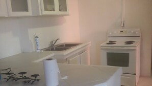 A small kitchen with white cabinets, a sink, and a stove. - BEYOND IMAGINATION (St. Thomas)