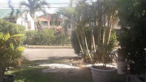 A courtyard with a tiled floor, potted plants, and a view of a street and buildings in the background. - BEYOND IMAGINATION (St. Thomas)