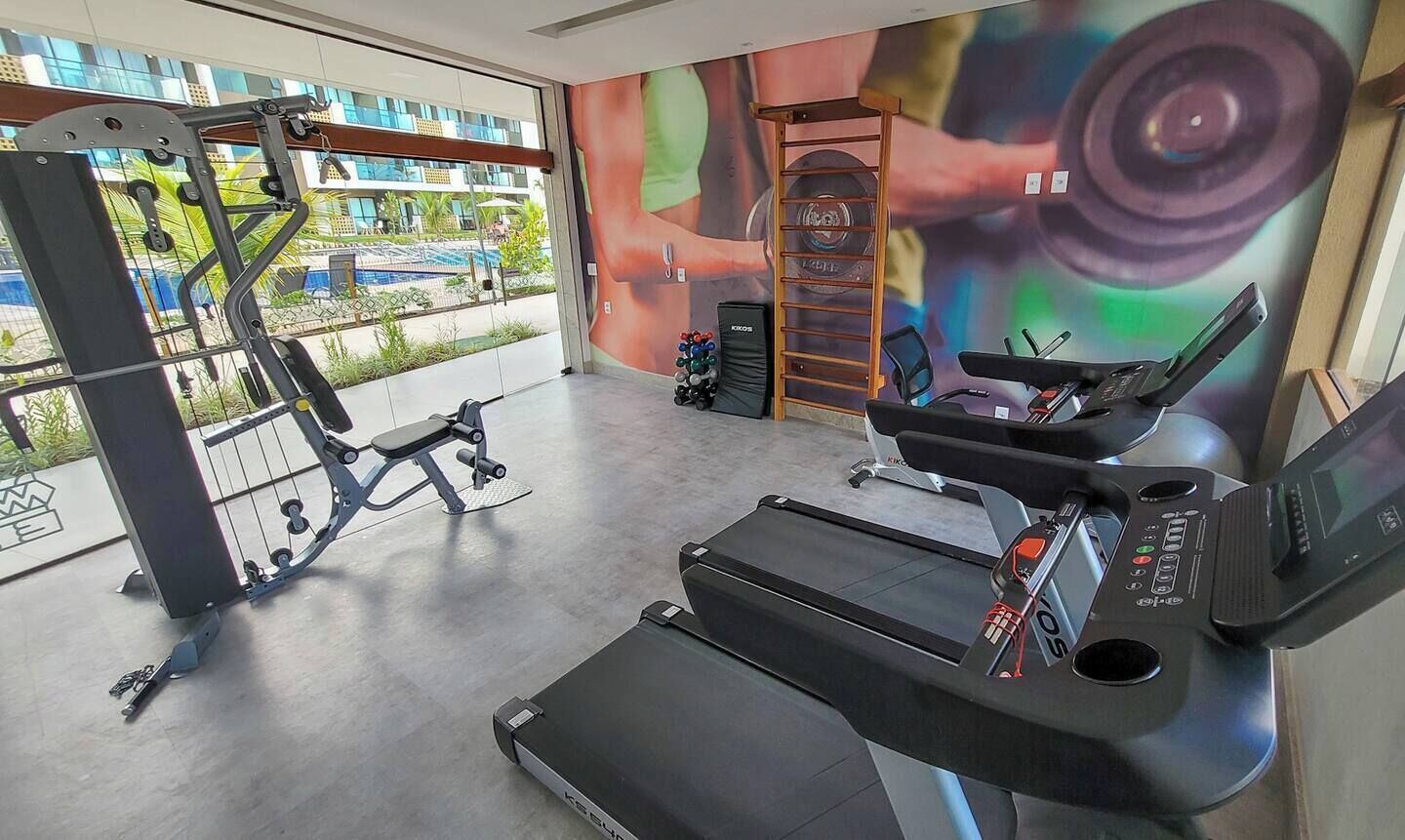 Un gimnasio con cinta de correr, banco de pesas y máquina de ejercicios.