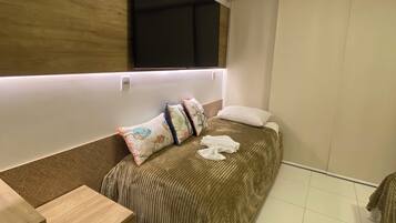 Un dormitorio moderno con cama, mesita de noche y televisión integrada.