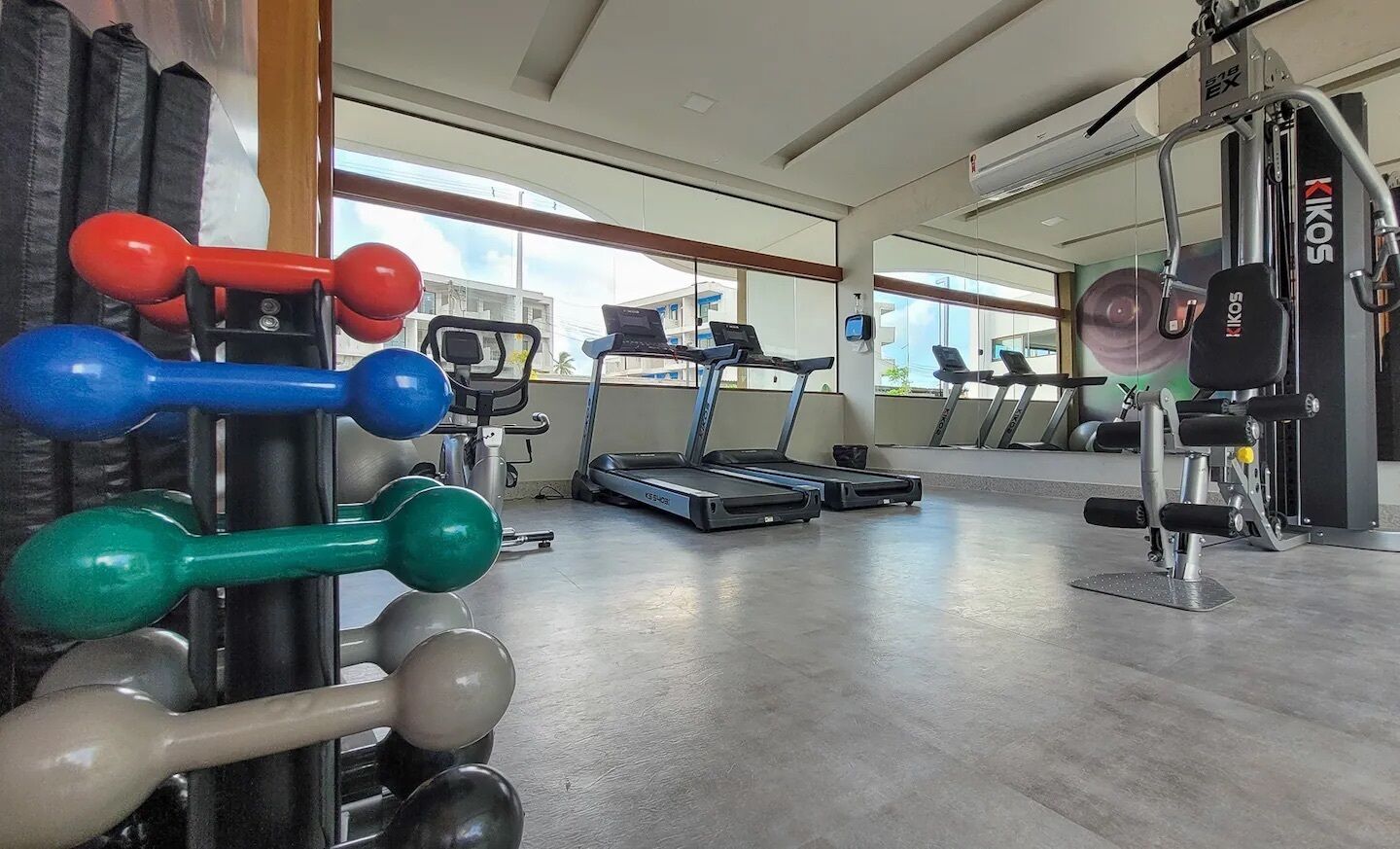 Un gimnasio con equipo de ejercicio, cintas de correr y un espejo grande.
