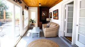 Un salon chaleureux avec un plafond en bois, un canapé beige, une table basse blanche et une grande fenêtre.