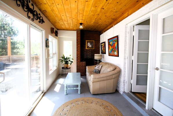 Un salon chaleureux avec un plafond en bois, un canapé beige, une table basse blanche et une grande fenêtre.