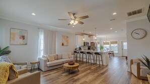 A spacious living room with a sofa, coffee table, and a dining area with bar stools.