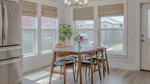 A kitchen with a wooden table, chairs, a refrigerator, and a chandelier.