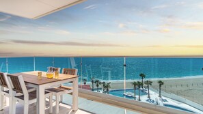 Un balcon avec une table et des chaises donnant sur une plage et l’océan.