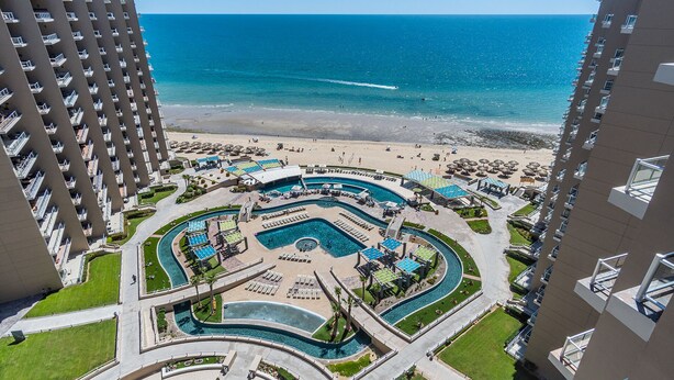 Un resort con un área de piscina central, varias piscinas y una playa.