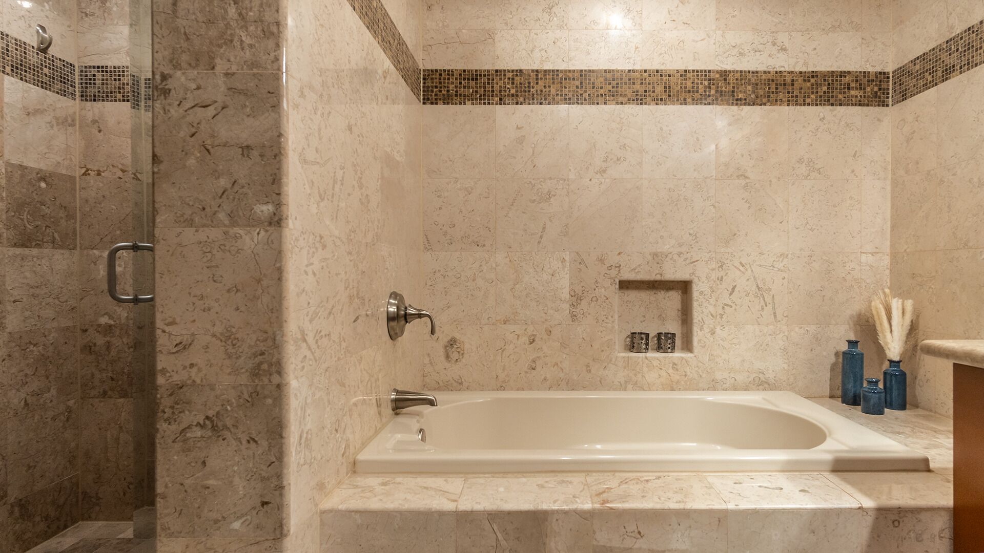 Une salle de bain équipée d’une baignoire, d’un espace douche et d’une petite étagère où sont rangés les articles de toilette.