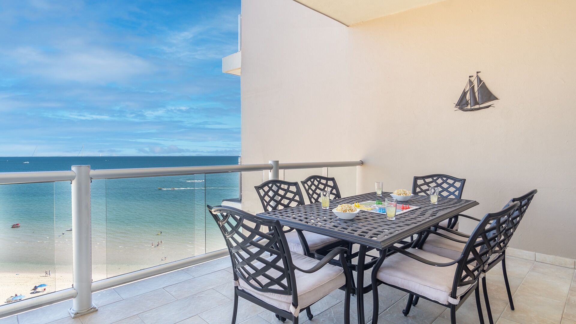 Un balcón con mesa y sillas con vista a la playa.