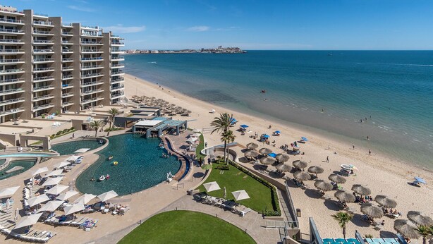Ein Hotel mit großem Pool, Strand und Meerblick.