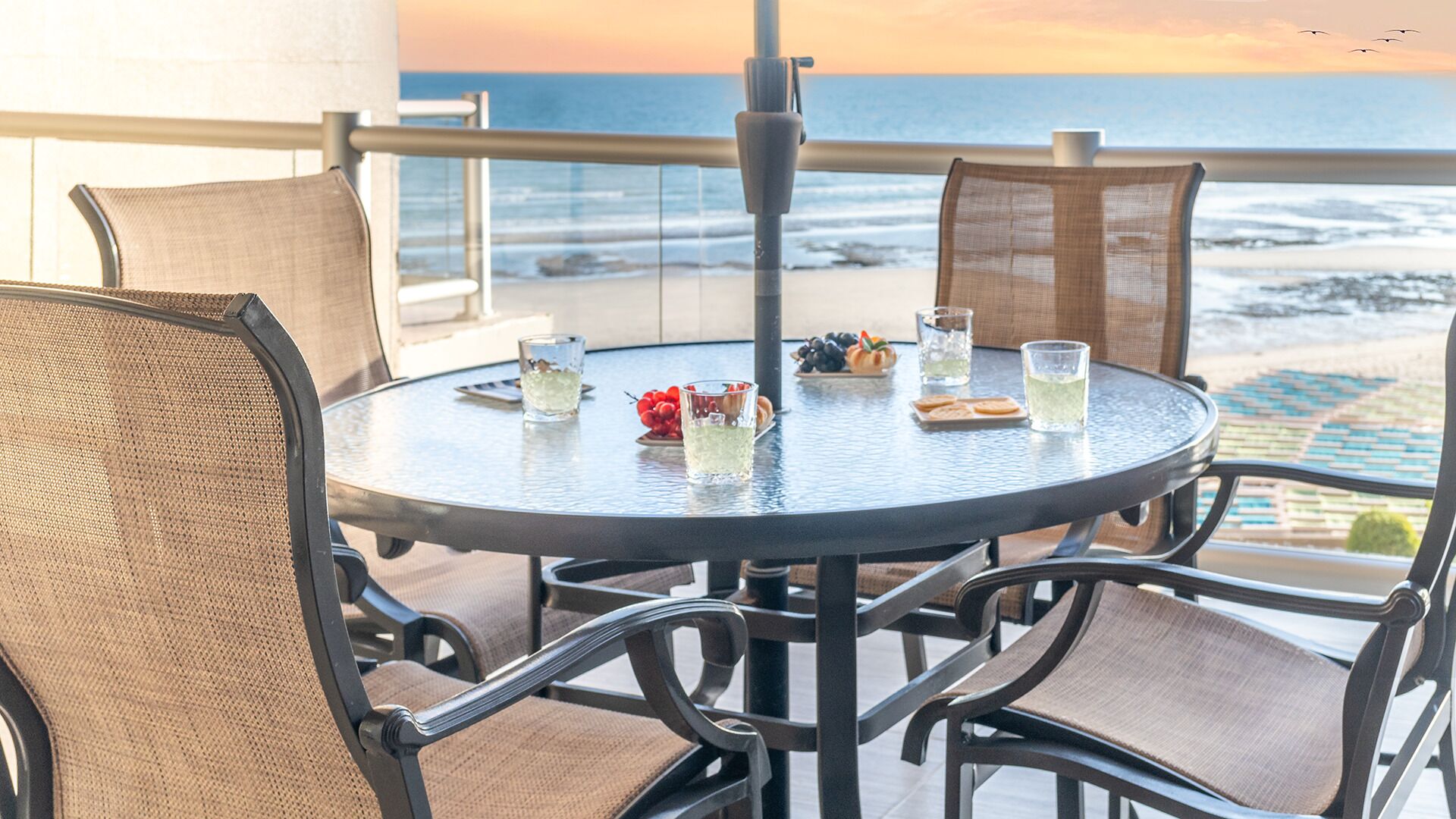 Ein runder Tisch mit Stühlen auf einem Balkon mit Blick aufs Meer.