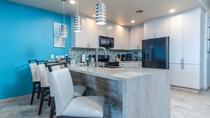 A modern kitchen with a central island, white cabinetry, and a blue accent wall. - Las Palomas 2 BR 2 BA Coronado 1204 (Puerto Peñasco)
