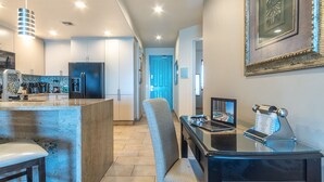 A modern kitchen with a central island, a dining area with a laptop, and a blue door leading to another room. - Las Palomas 2 BR 2 BA Coronado 1204 (Puerto Peñasco)