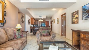 A spacious living room with a sofa set, a coffee table, and a dining area in the background.