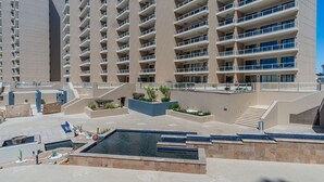 A modern hotel with multiple floors, a central courtyard with a pool, and outdoor seating areas.