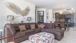 Una sala moderna con un sofá modular, un reposapiés y decoración en la pared.