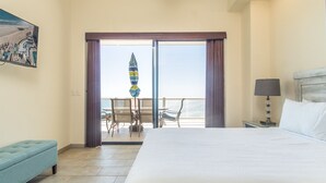 Un cuarto de hotel con una cama grande, un balcón con mesa y sillas, y un cuadro en la pared.