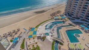 Un resort con un amplio espacio de piscina, playa y un edificio de gran altura.