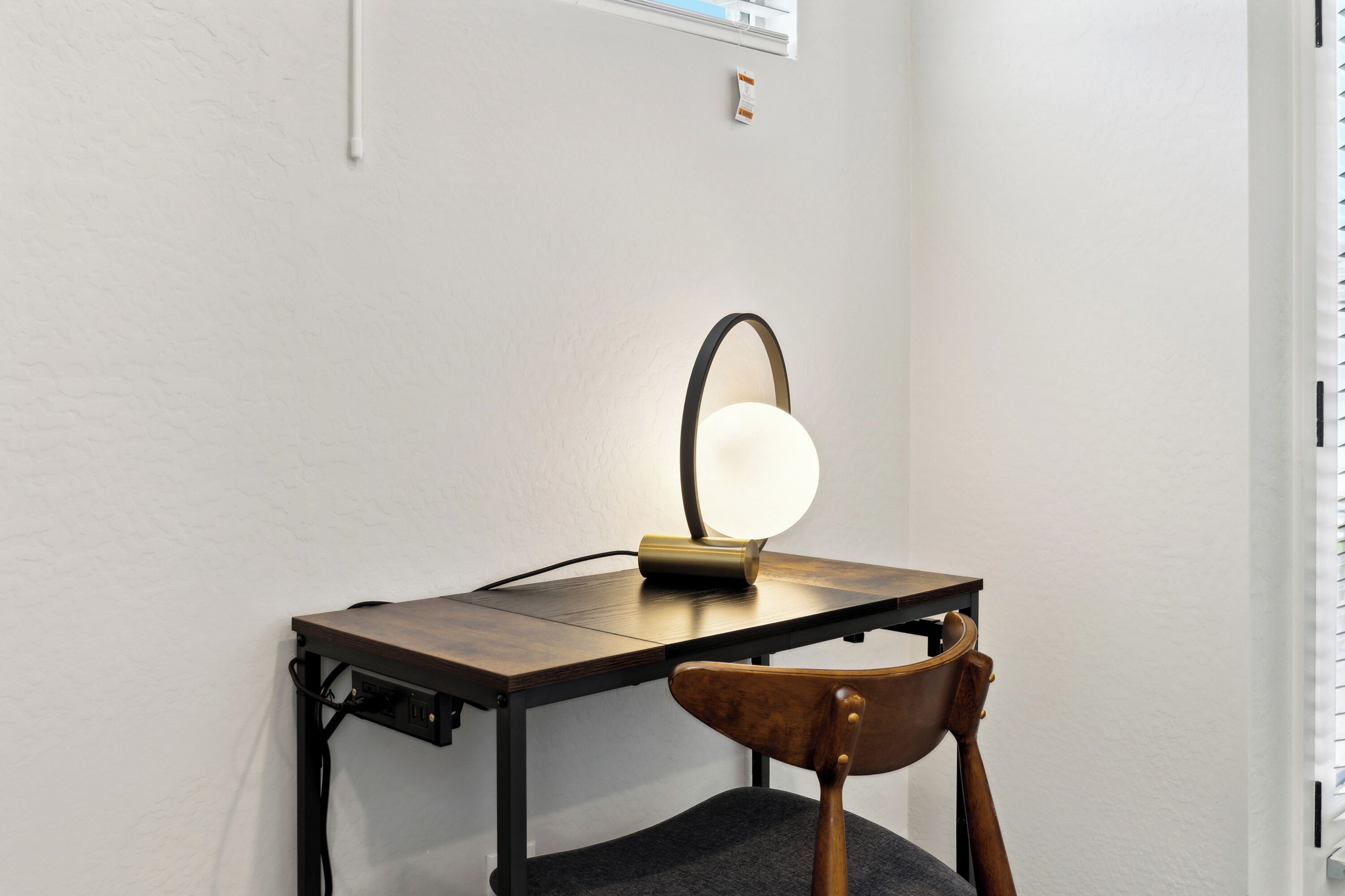 A desk with a lamp, a chair, and a power outlet.