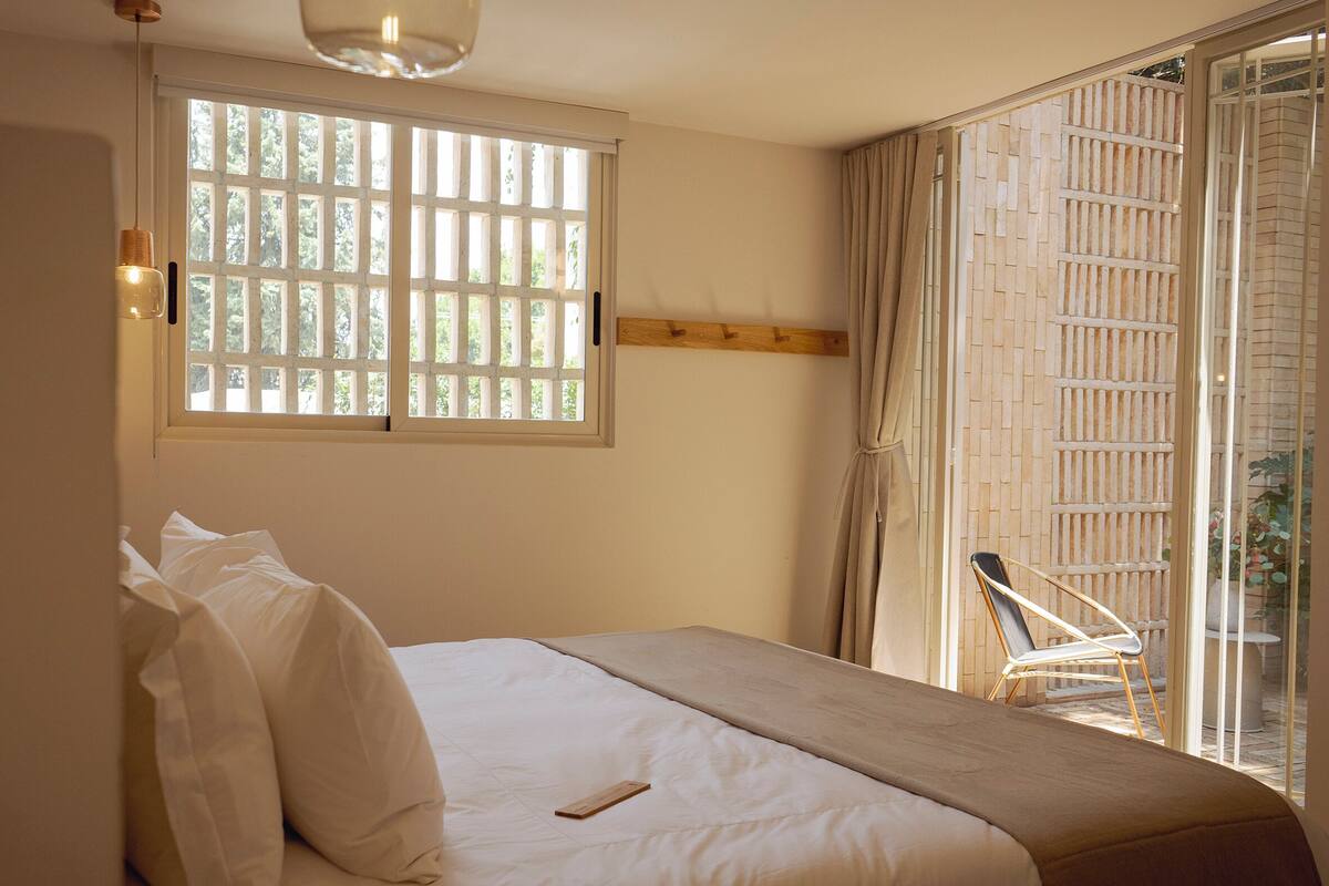 A bedroom with a bed, a window, and a view of the outside.