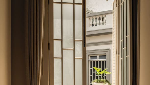 A doorway with a frosted glass panel, a potted plant, and a white balustrade. - Hotel Casa Cuenca (Mexico City)