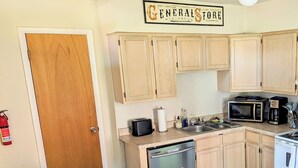 Una cocina con gabinetes de madera, un microondas, una estufa, un lavavajillas y un refrigerador.