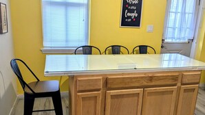 Una cocina con una isla de vidrio, armarios de madera y una silla negra.