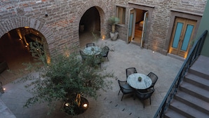 An outdoor courtyard with stone flooring, a central round table with chairs, and a potted plant. - Hotel Casa Aranzazu San Luis Potosi (San Luis Potosi)