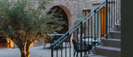 A courtyard with stone walls, a staircase, and outdoor seating.