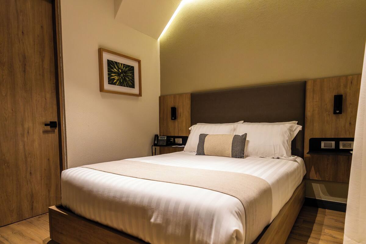 A modern bedroom with a wooden bed, a bedside telephone, and a framed picture on the wall.