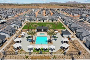 Un quartier résidentiel composé de maisons modernes disposées en rangées, avec une piscine centrale et des espaces de détente en plein air.