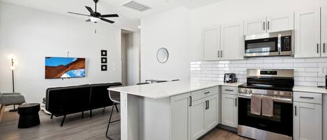 A modern kitchen with white cabinetry, a built-in microwave, and a stainless steel oven.